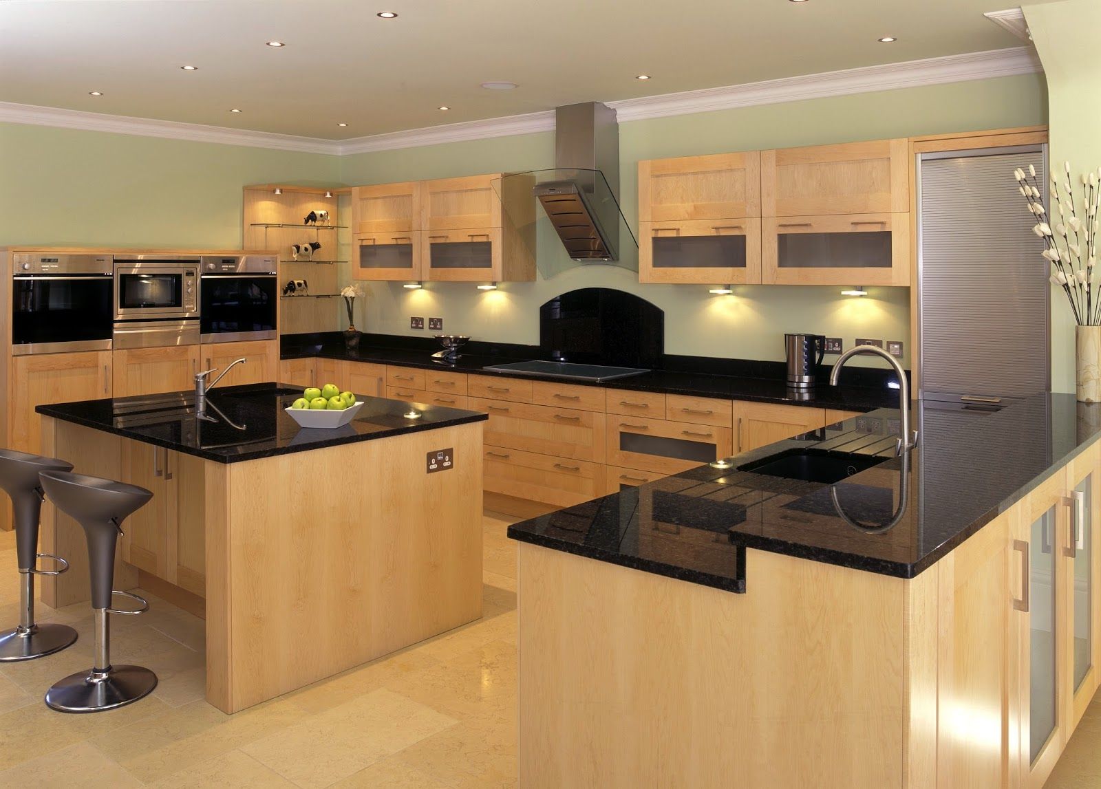 cocina moderna y bien iluminada con gabinetes de madera y encimeras negras, que ejemplifica una combinación de elementos de diseño natural y contemporáneo. Es interesante porque resalta un diseño de cocina funcional y estéticamente agradable que equilibra los electrodomésticos modernos con materiales naturales.