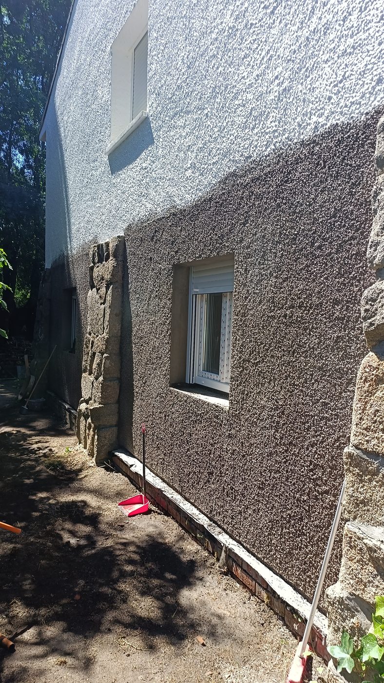 Terreno rebajado al pie de la fachada de granito y gotelé durante el replanteo de la obra en Becerril de la Sierra