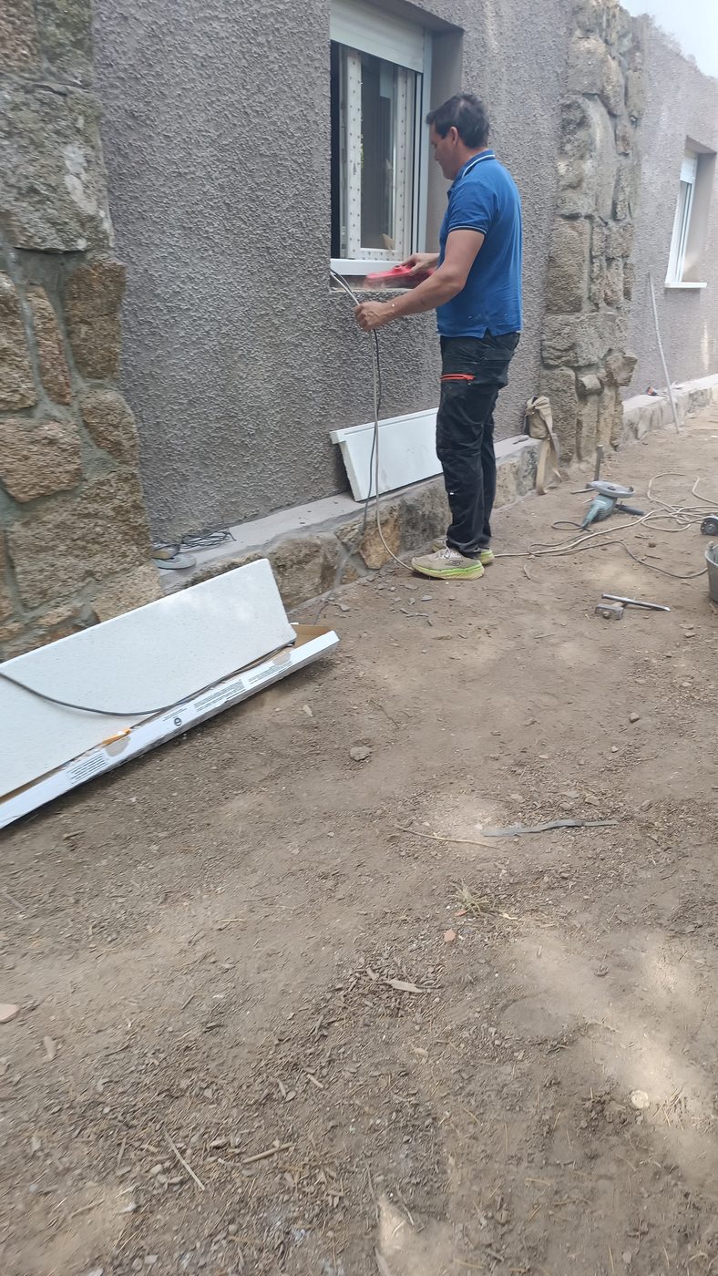 Operario trabajando en el hueco de ventana durante el cerramiento del porche en Becerril de la Sierra