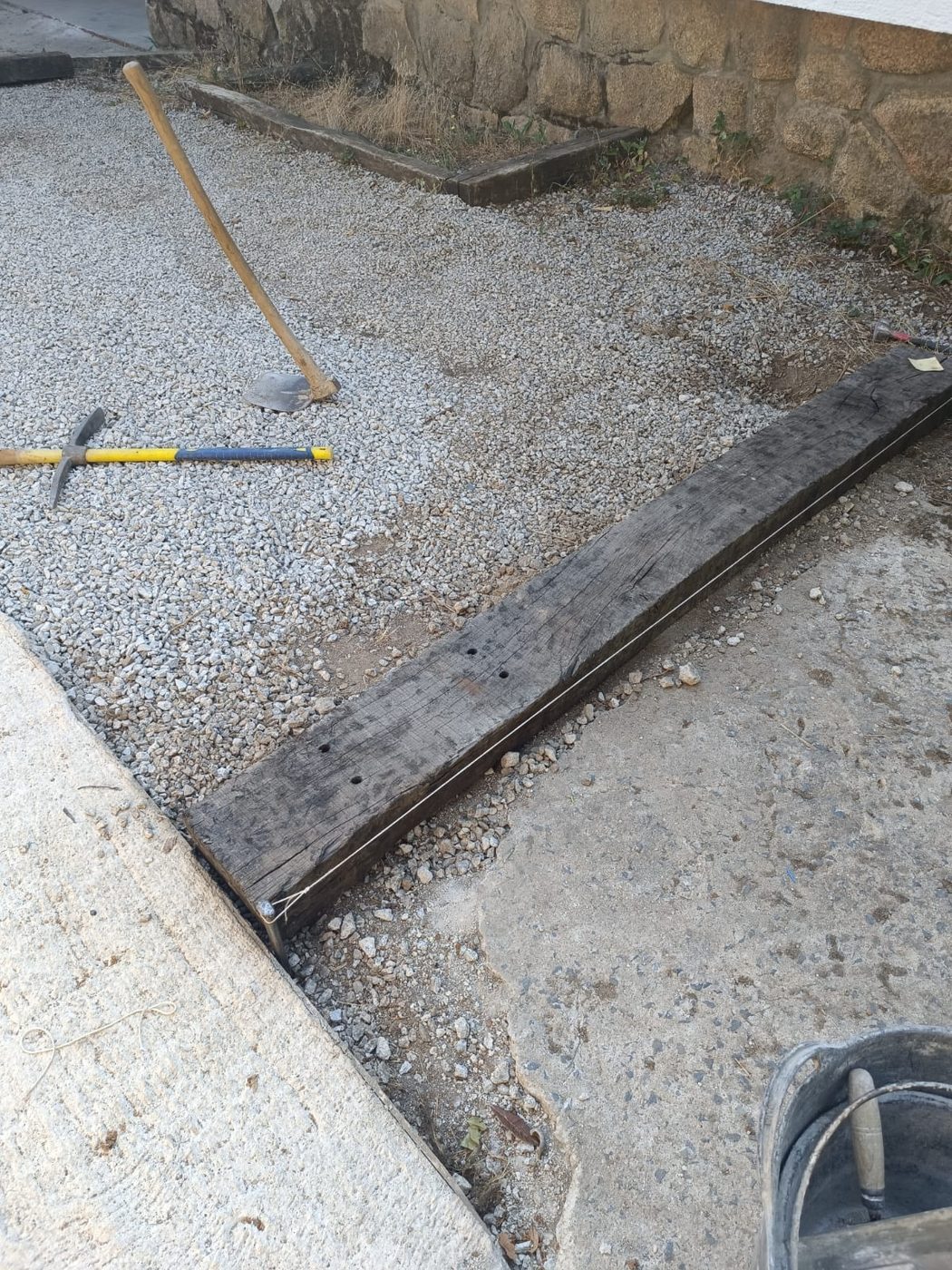 Traviesa de madera usada como bordillo y encofrado, con cordel de replanteo antes de hormigonar