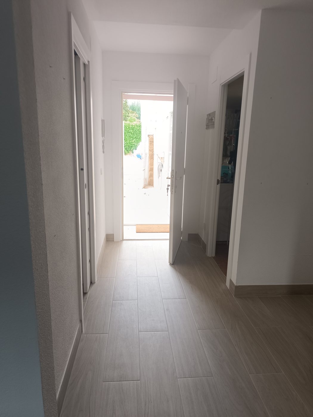 Pasillo terminado con porcelánico imitación madera y puertas lacadas blancas en Moralzarzal