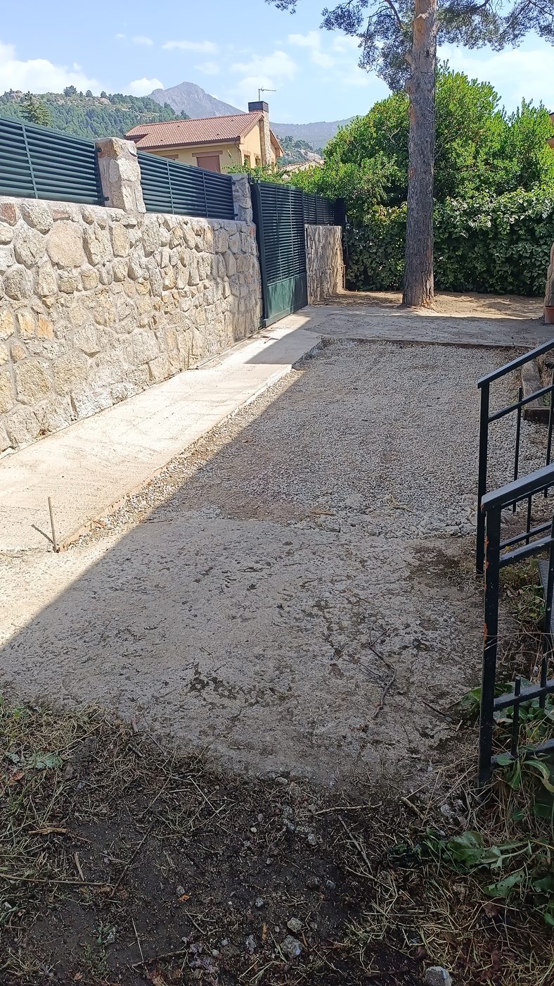 Rampa de acceso de hormigón terminada junto al muro de mampostería de granito en Becerril de la Sierra
