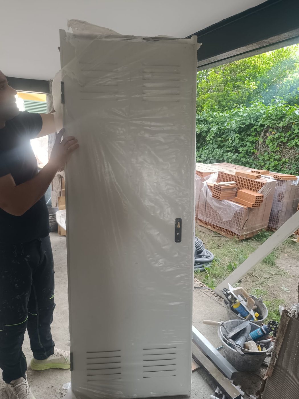 Puerta metálica con rejillas de ventilación para el trastero, junto a palés de ladrillo hueco