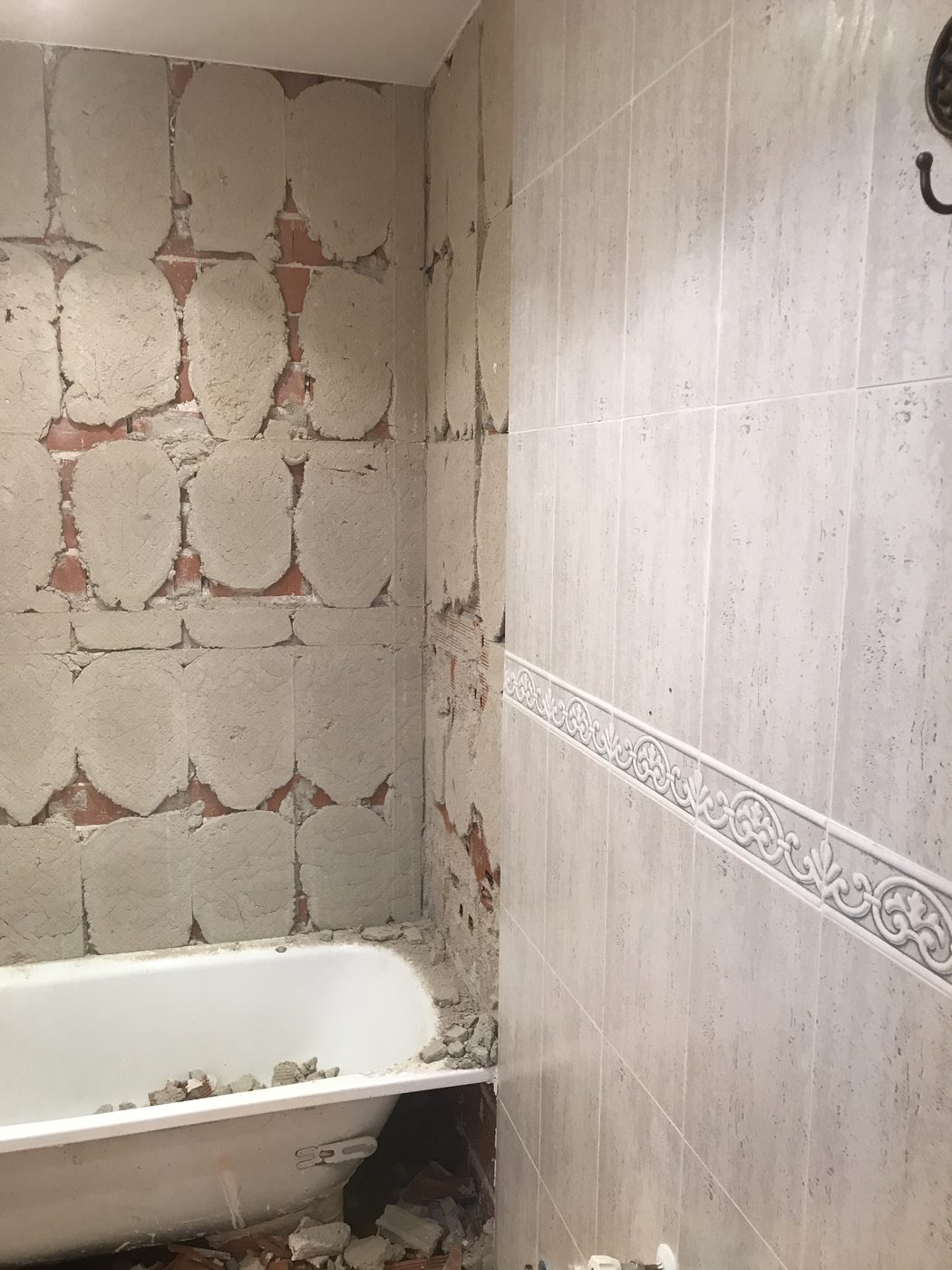 Demolición parcial: contraste entre pared picada y alicatado antiguo con cenefa