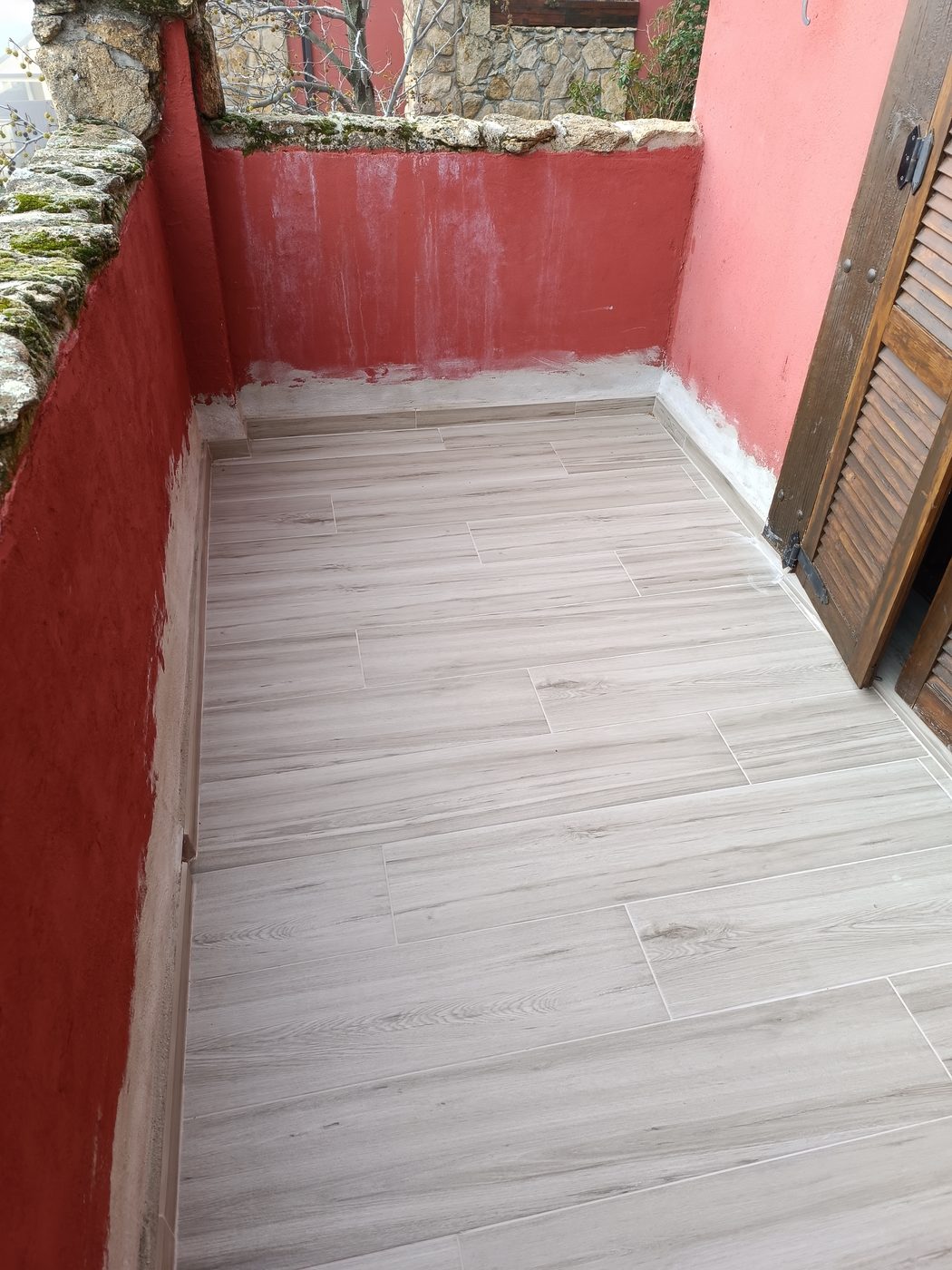 Terraza terminada con porcelánico imitación madera y rodapié perimetral